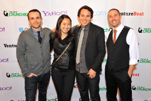 Eine Gruppe strahlender Menschen posiert vor einem Sponsorenbanner für die Kamera.