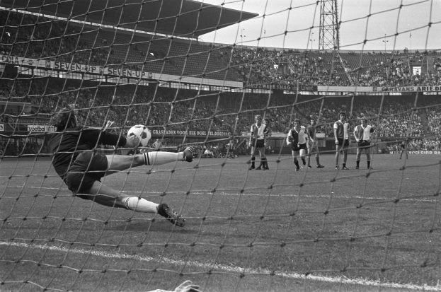 Schwarz-weiß-Foto eines Fußball-Torwarts, der einen Ball hält, während er einen Abschlag vor einem Stadionpublikum macht.