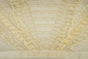 Nahaufnahme eines weißen Kleides mit detaillierter Spitzenverzierung, mit zarten Mustern und einem leichten, luftigen Stoff, der für den Sommer geeignet ist.