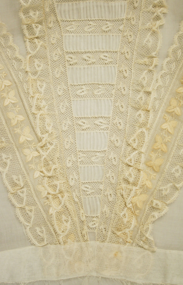 Nahaufnahme eines weißen Kleides mit detaillierter Spitzenverzierung, mit zarten Mustern und einem leichten, luftigen Stoff, der für den Sommer geeignet ist.