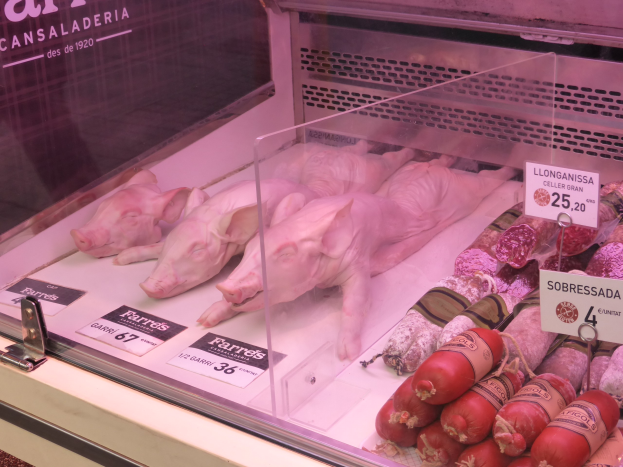Vitrine voller verschiedener Schweine- und Wurstsorten, jede mit einem Preisetikett versehen.