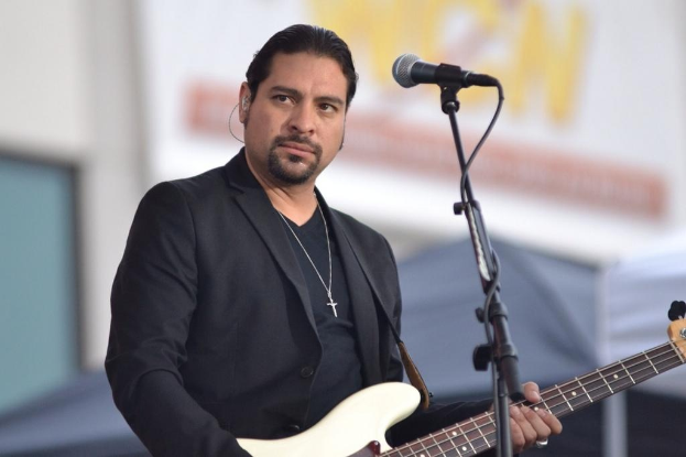 Ein Mann in einem schwarzen Anzug spielt eine Bassgitarre vor einem Mikrofon auf dem New Orleans Jazz & Heritage Festival.