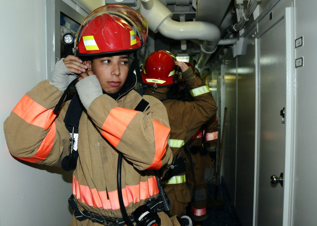 Feuerwehrleute in Uniform in einem Raum mit Rohren und Equipment während eines Trainings.