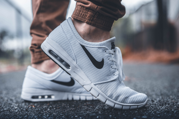 Eine Person in schwarzen, weißen und grauen Nike SB Stefan Janoski Max-Schuhen vor einem unscharfen, träumerischen Hintergrund.