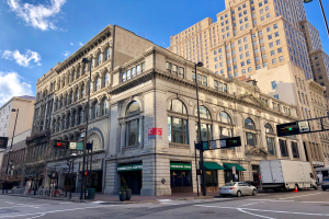 Ein großes Eckgebäude, ehemals ein Starbucks, umgeben von anderen Gebäuden, Straßenlaternen, Verkehrszeichen, Fahrzeugen, Fußgängern, Bäumen und einem bewölkten Himmel in Chicago.