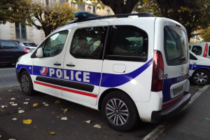 Polizeifahrzeug auf einer Stadtstraße geparkt mit Gebäuden, Bäumen und welken Blättern.