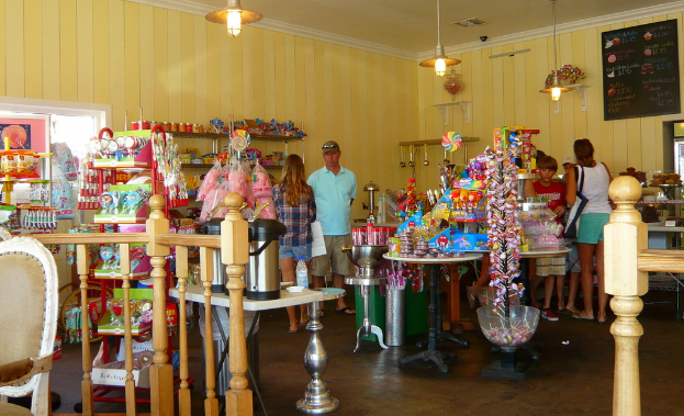 Eine Gruppe von Menschen steht vor einem Geschäft, das Lutscher, Süßigkeiten und Backwaren anbietet.