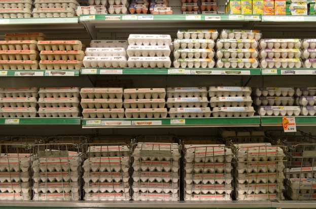 Ein Supermarktregal mit ordentlich angeordneten Eiertrays neben Obst, Gemüse und anderen Lebensmitteln.