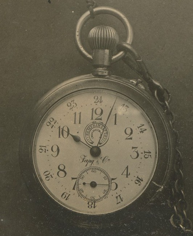 Ein Schwarz-Weiß-Foto eines antiken Taschenuhr mit einer Kette, das eine nummerierte Uhr zeigt.