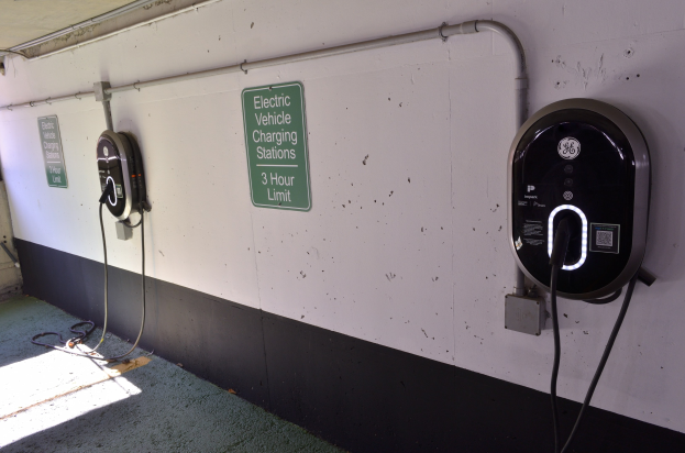 Elektrofahrzeug-Ladestationen an einer Wand in einer Tiefgarage mit Informationsschildern darüber.