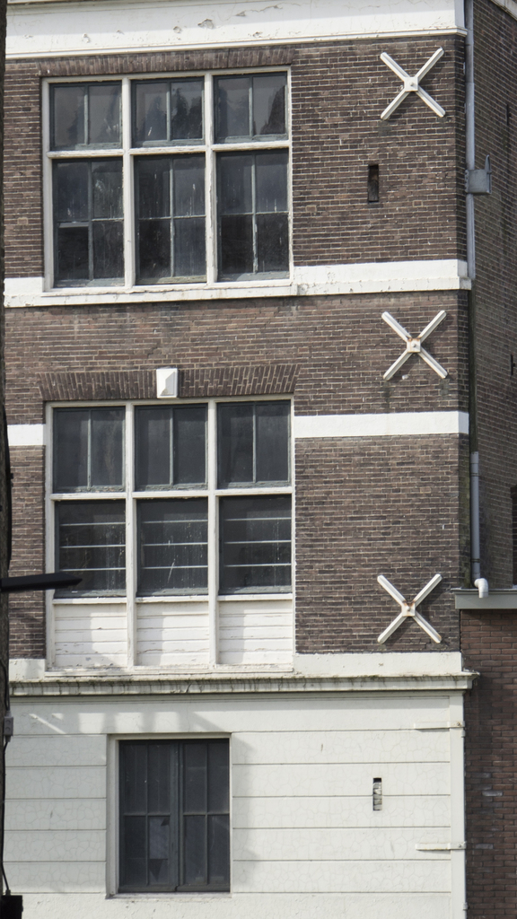 Ein Geb├Ąude mit mehreren Fenstern und sichtbaren Rohren an seiner ├Ąu├čeren Seite.