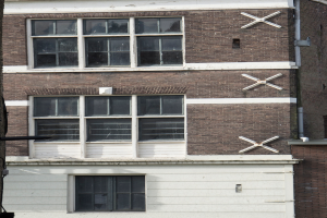 Ein Geb├Ąude mit mehreren Fenstern und sichtbaren Rohren an seiner ├Ąu├čeren Seite.