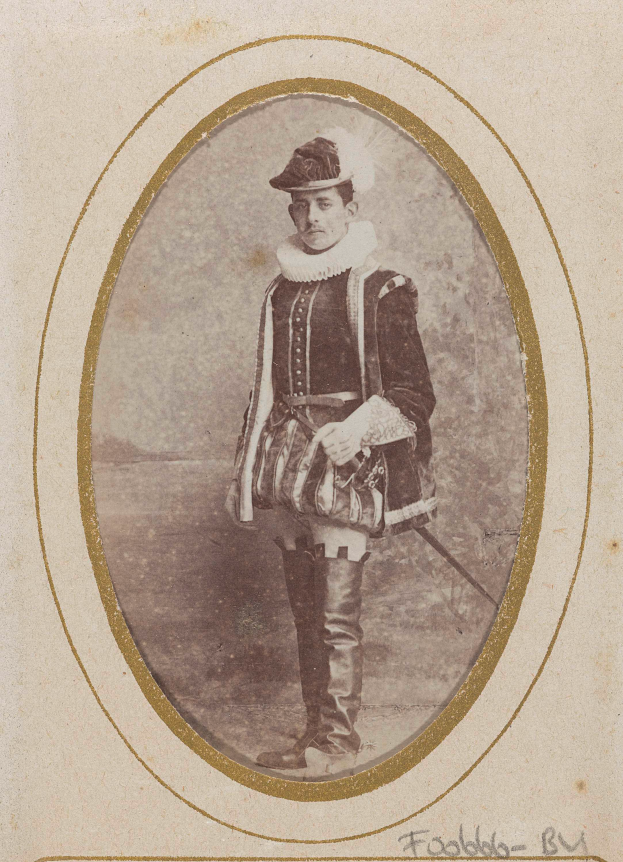 Ein altes Foto eines Mannes in traditioneller schottischer Kleidung, einschließlich eines Kilts, weißem Hemd, schwarzem Weste und schwarzem Hut, der mit entschlossener Miene steht und ein Schwert hält.