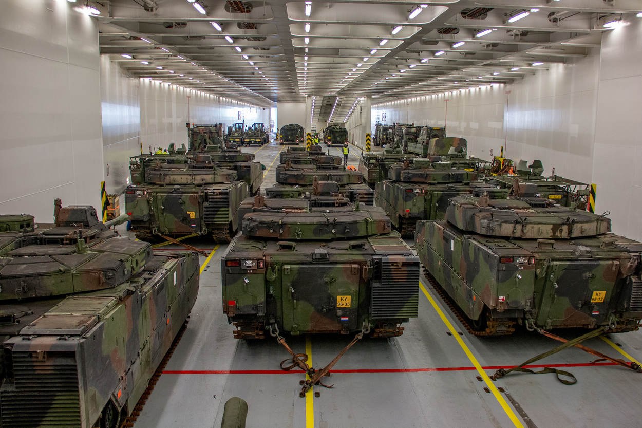 Ein grosser Militaraustellungsraum mit Reihen von Militarafahrzeugen, Wanden auf beiden Seiten und Deckenleuchten.