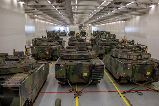 Ein grosser Militaraustellungsraum mit Reihen von Militarafahrzeugen, Wanden auf beiden Seiten und Deckenleuchten.