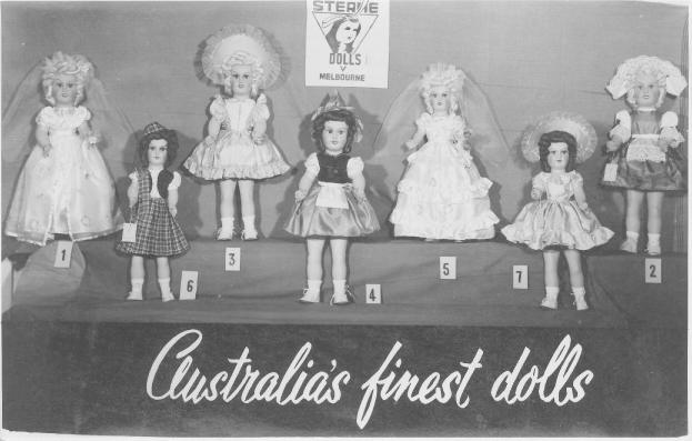 Ein Schwarz-Weiß-Foto einer Reihe australischer Puppen, jeweils mit einzigartigen Outfits und Frisuren, mit einem Plakat mit Text und Logo im Hintergrund.