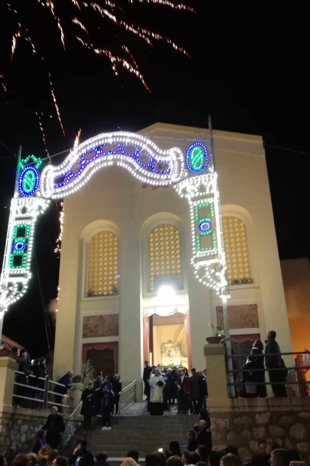Menschen vor einem Gebäude mit beleuchteten Bögen, Treppen und Topfpflanzen bei einem Silvesterfeuerwerk