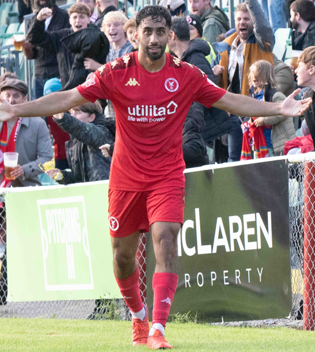 Ein Fußballer in roter Uniform rennt mit ausgebreiteten Armen auf einem Feld, im Hintergrund ist eine Zuschauermenge und ein Banner mit der Aufschrift "Middlesbrough FC v Swansea City - Sky Bet Championship" zu sehen.