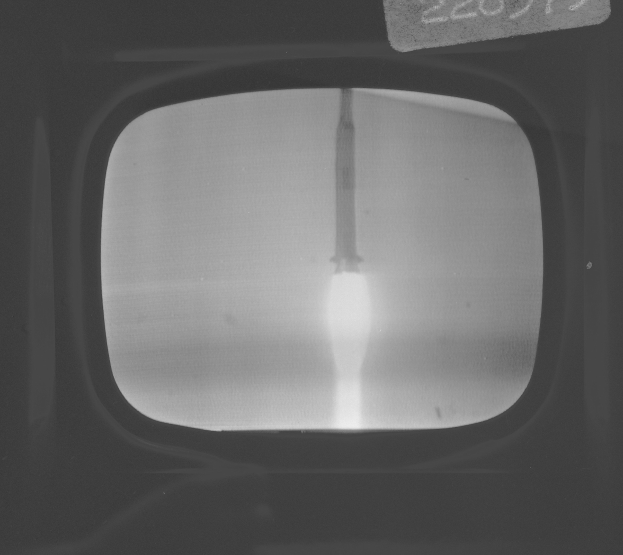 Schwarzes und weißes Foto eines Fernseherbildschirms mit einem Raketenstart durch das Fenster, mit Text oben.