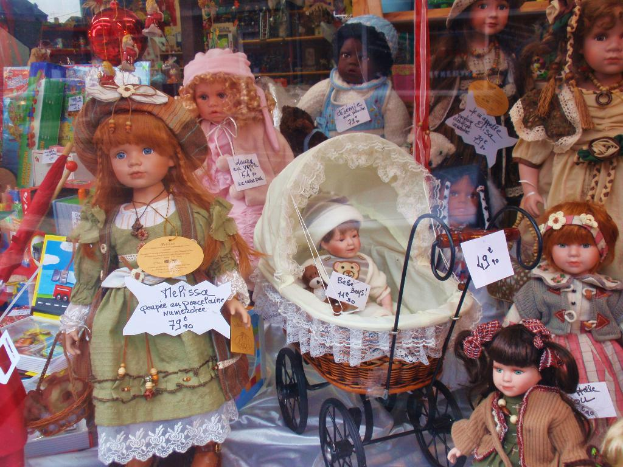 Mehrere Barbie-Puppen in bunten Kleidern, ein Rollstuhl, Schachteln, ein Schirm, Ständer, Banner und andere Produkte.