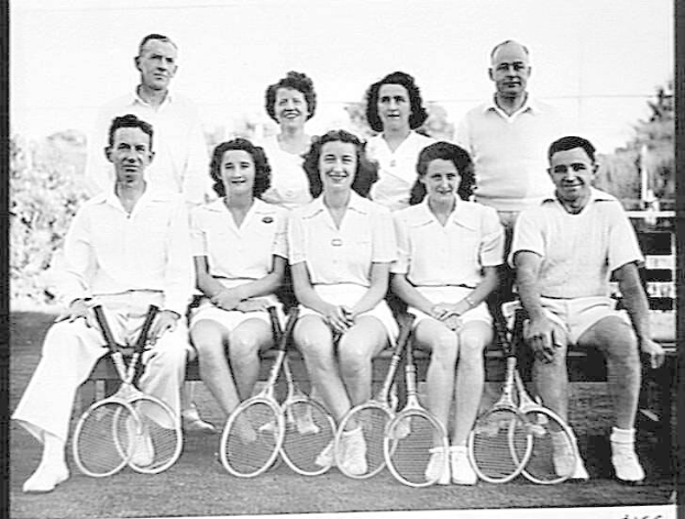 Eine Gruppe von Menschen, die auf einer Bank sitzen, lächeln und Tennisrackets halten, mit Bäumen und einem klaren Himmel im Hintergrund; Text unten lautet "Tennis Hall of Fame".