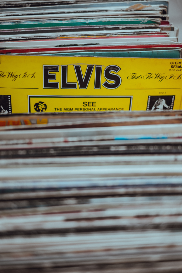 Ein Stapel Elvis-Presley-Platten ordentlich auf einem Tisch gestapelt, mit einigen überlappenden und lesbaren Titeln gegen einen leicht unscharfen Hintergrund.