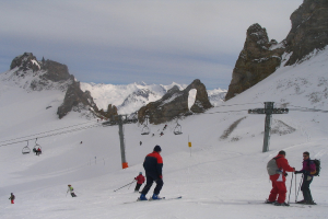 Menschen in Pullovern fahren Ski auf Eis, mit einer Seilbahn, Bergen und einem bewölkten Himmel im Hintergrund.