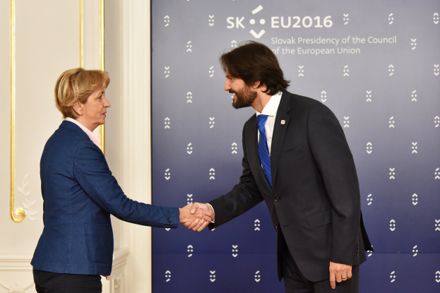 Bundeskanzlerin Angela Merkel und Bundespr├Ąsident Joachim Gauck geben sich die Hand vor einer Wand mit einem "EU-Gipfel"-Schild und einer Tür im Hintergrund, beide l├Ącheln.