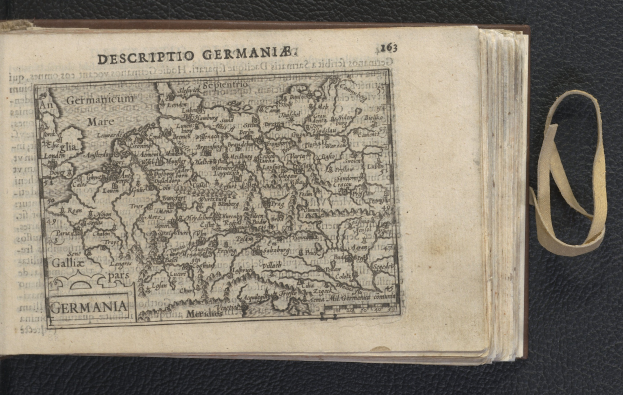 Offenes Buch mit einer Deutschlandkarte auf einer schwarzen Oberfläche, das eine Seite mit Text und eine historische Karte zeigt.
