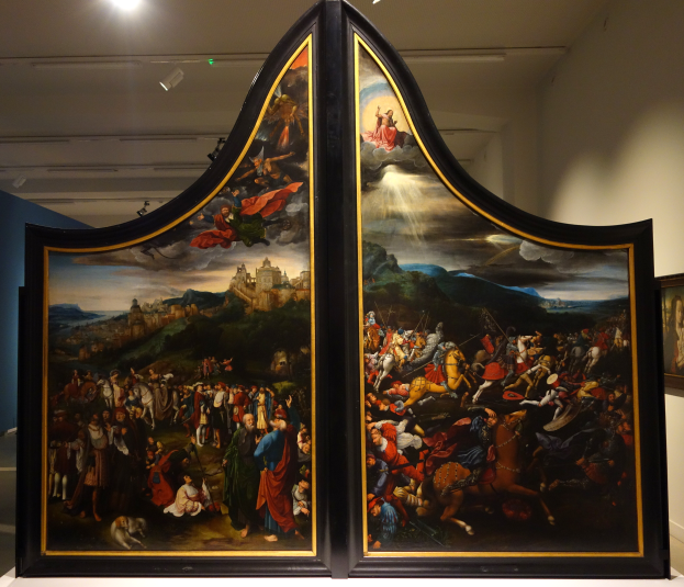 Ein großes, farbenfrohes Triptychon-Gemälde in einem Museum ausgestellt, mit einem Foto-Rahmen an der benachbarten Wand und Deckenleuchten.