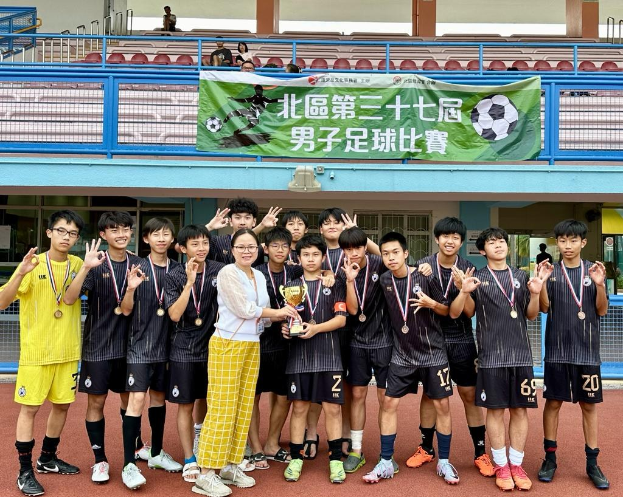 Gruppe junger Männer in Fußballtrikots auf einem Feld, mädelliert und einen Pokal haltend, mit einem Banner im Hintergrund, das 'Yokohama U-16 Jungen Fußballmannschaft' lautet.