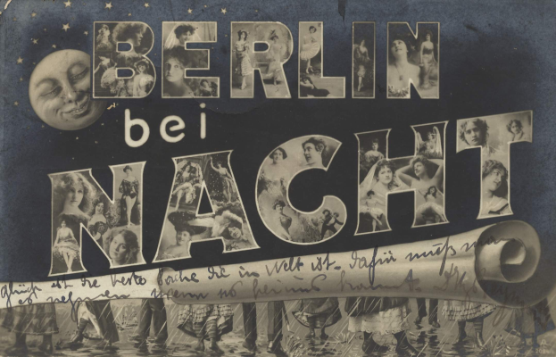 Schwarzes und weißes Foto einer Gruppe von Menschen, die vor einem "Berlin Bei Nacht"-Schild mit einem Mond im Hintergrund lachen und strahlen.
