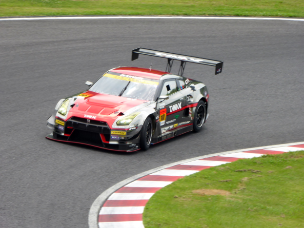 Ein Nissan GT-R Nismo GT3-Rennwagen auf der Nürburgring 24 Stunden-Strecke, mit grünem Gras auf beiden Seiten des Asphalts.